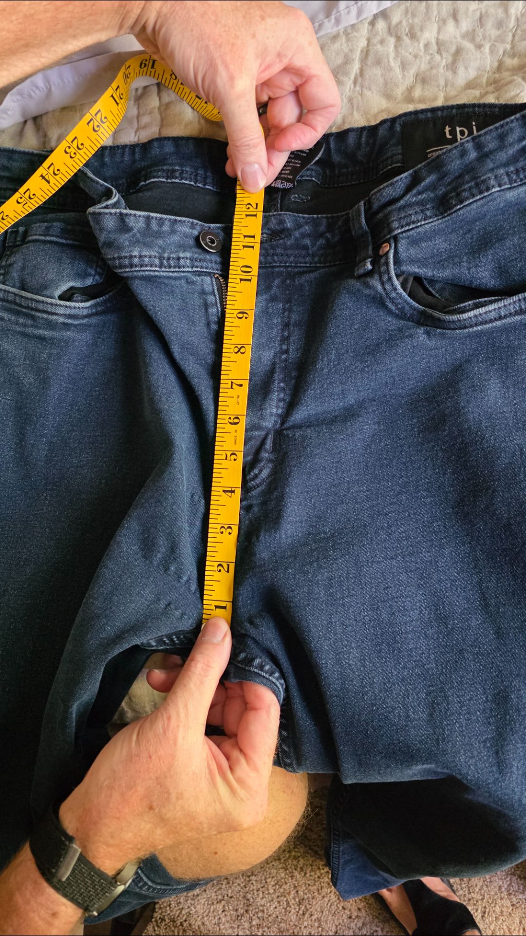 Measuring the front rise on a pair of jeans - The Tall Take The Perfect Jean laid flat with a yellow tape measure running from the top of the waistband down to the crotch seam, reading 12.5 inches of front rise on a size 38