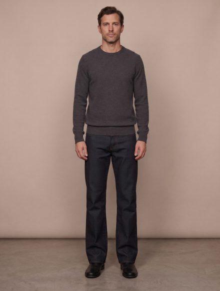 A tall man in a charcoal crewneck sweater and dark denim showing correct sleeve and body proportions